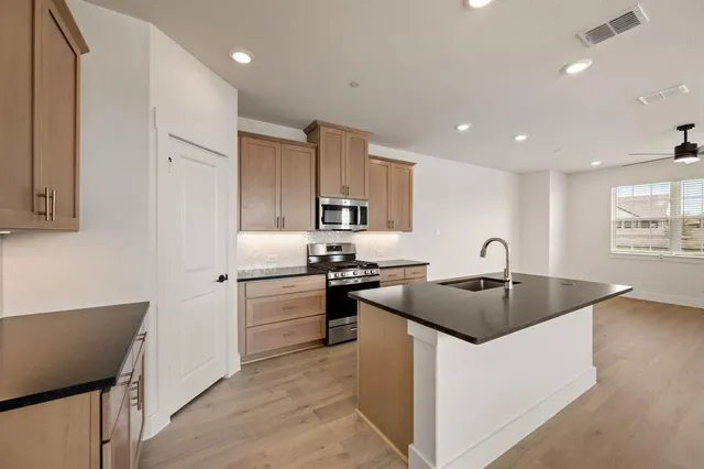a kitchen with stainless steel appliances granite countertop a stove a sink and a refrigerator