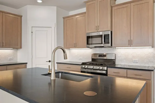 a kitchen with stainless steel appliances granite countertop a stove a sink and a refrigerator