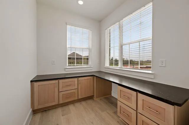 an empty room with wooden floor ceiling fan and windows