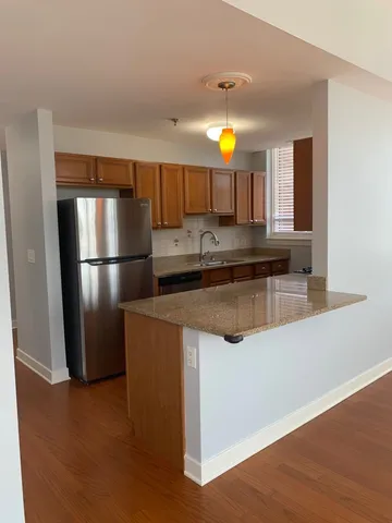 a kitchen with stainless steel appliances granite countertop a refrigerator a sink a stove and a wooden floors