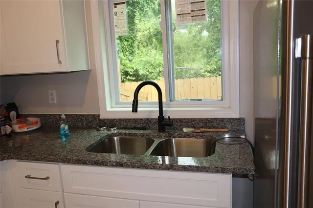 a kitchen with granite countertop a sink a stove and cabinets