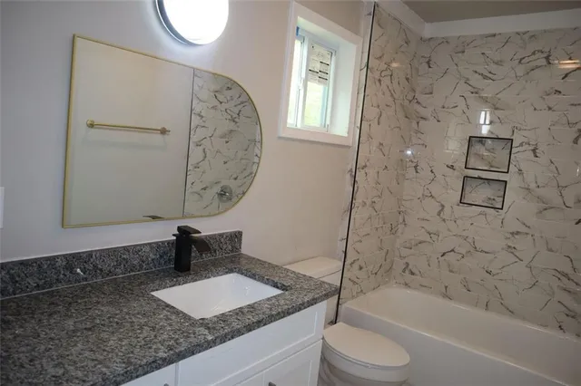 a bathroom with a granite countertop sink toilet and shower