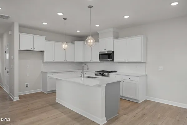 a kitchen with stainless steel appliances granite countertop a sink a stove a refrigerator and white cabinets with wooden floor