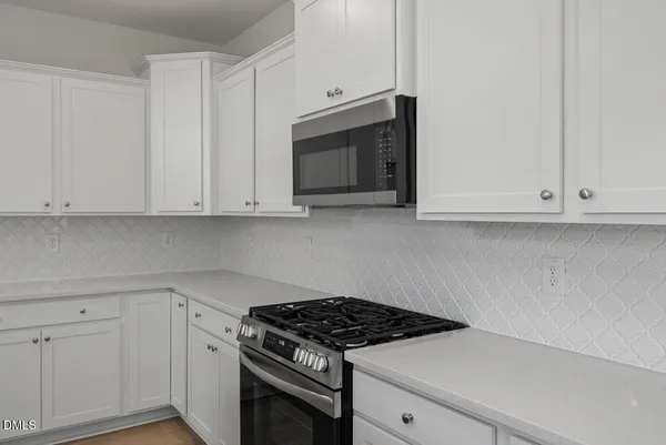 a kitchen with white cabinets and a stove with wooden floor