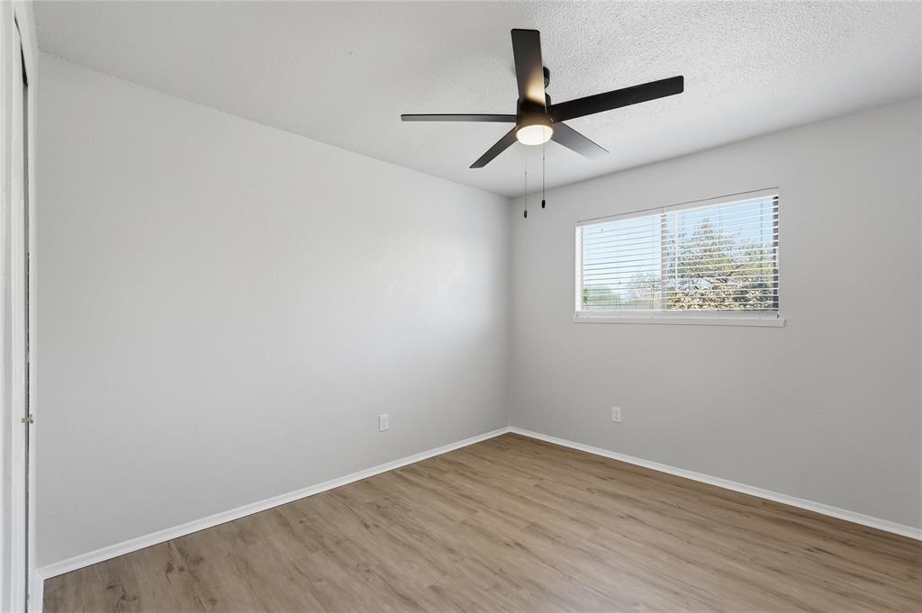 5514 Round Rock Road Garland, TX 75044 - Photo 26 of 37 an empty room with wooden floor ceiling fan and windows
