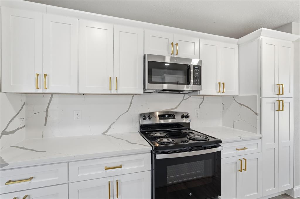 5514 Round Rock Road Garland, TX 75044 - Photo 10 of 37 a kitchen with stainless steel appliances a stove a microwave and cabinets
