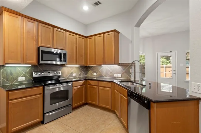 a kitchen with stainless steel appliances granite countertop a stove a sink and a microwave