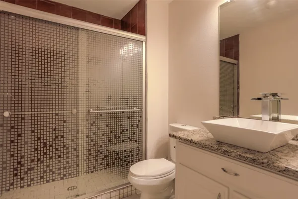 a bathroom with a granite countertop toilet a sink and a mirror