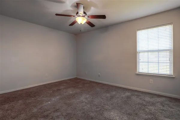 an empty room with a chandelier fan and windows