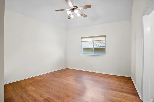 a view of a big room with wooden floor and a chandelier fan