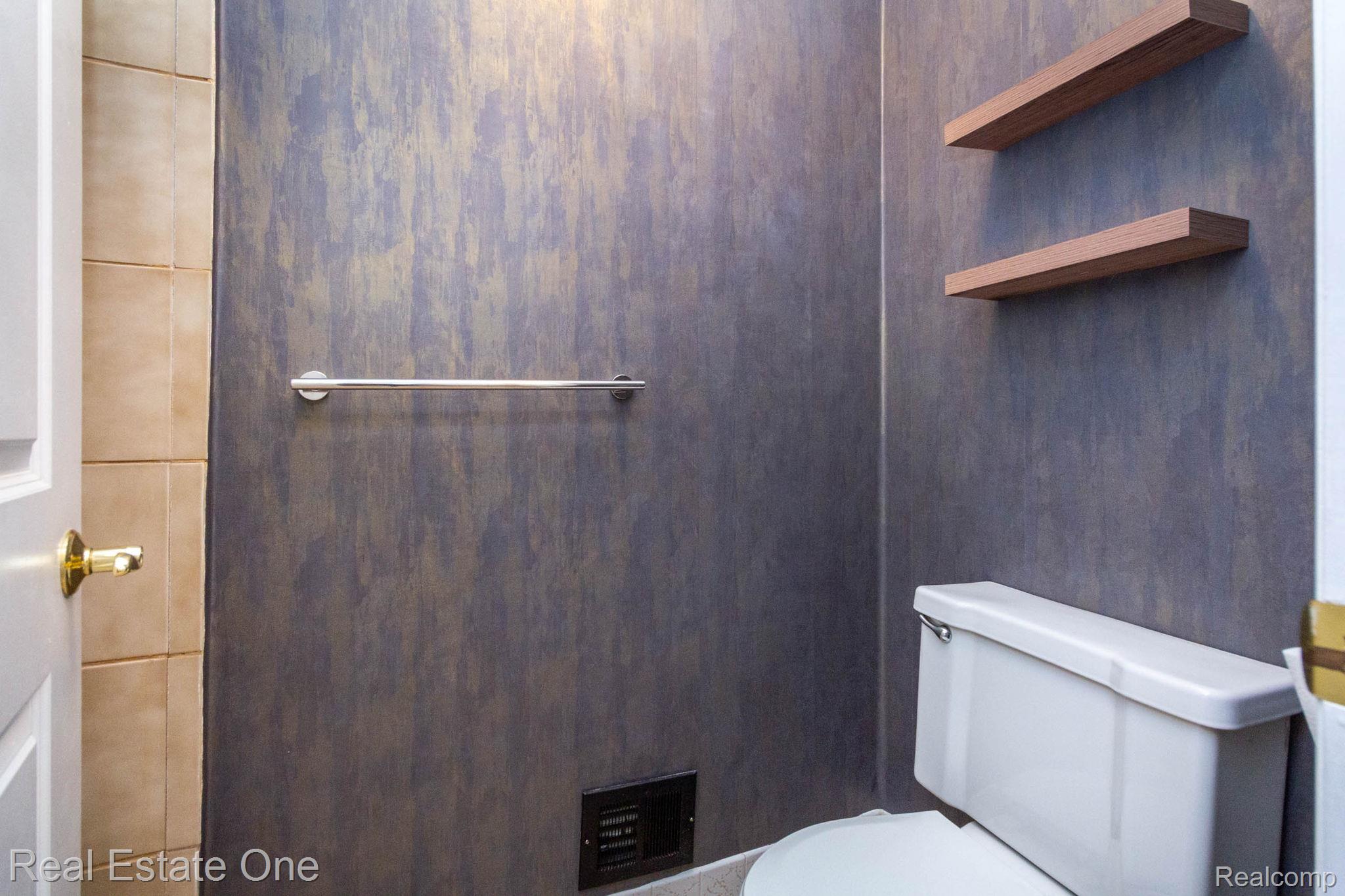 111 Manor Way Rochester, MI 48309 - Photo 19 of 36 Powder room featuring a white toilet, two floating wood shelves, and a chrome towel bar set against textured wallcovering