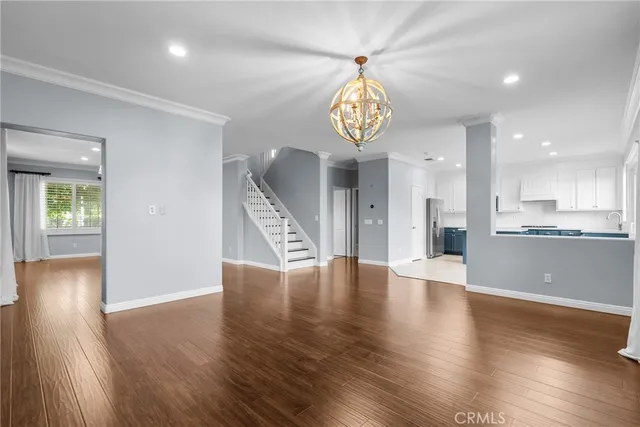 a large kitchen with stainless steel appliances granite countertop a stove top oven a sink dishwasher a refrigerator and white cabinets with wooden floor