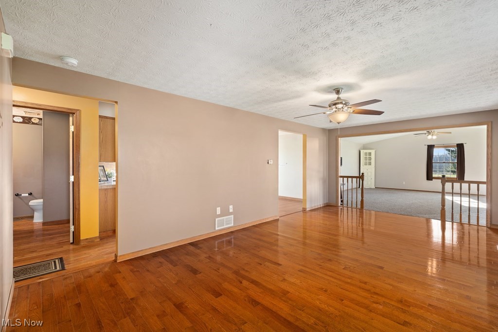 Spare room featuring hardwood / wood-style flooring, ceiling fan, and a textured ceiling