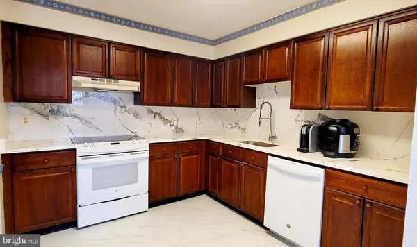 a kitchen with stainless steel appliances granite countertop wooden cabinets a sink and dishwasher a refrigerator with wooden cabinets