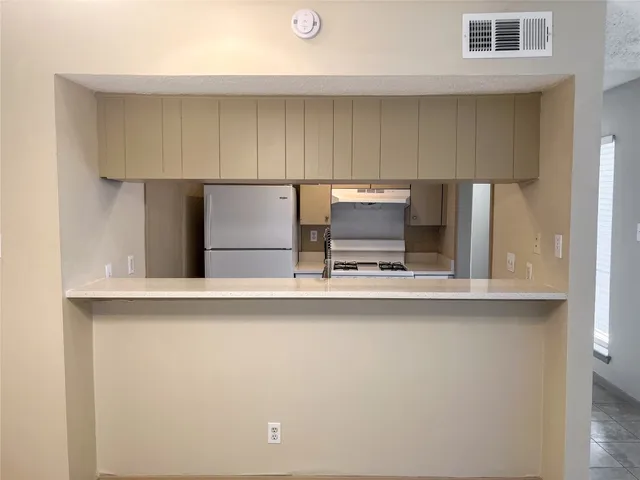 a kitchen with stainless steel appliances a sink a stove a refrigerator cabinets and a window