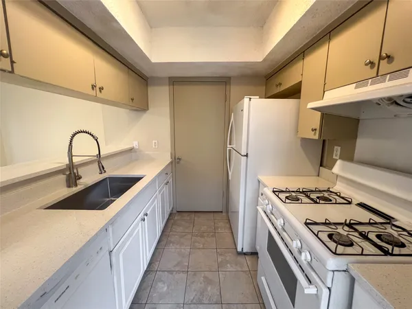 a kitchen with stainless steel appliances a sink a stove a refrigerator cabinets and a window