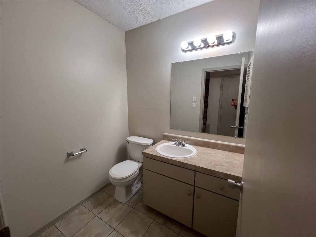 7206 Creekside Drive, Unit C Austin, TX 78752 - Photo 10 of 22 a bathroom with a granite countertop sink a toilet and a mirror