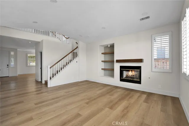 a view of an empty room with wooden floor fireplace and a window