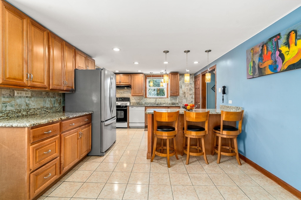87 Waldeck Road Milton, MA 02186 - Photo 8 of 21 a kitchen with stainless steel appliances kitchen island granite countertop a table and chairs in it