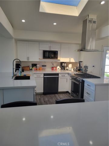 a kitchen with kitchen island stainless steel appliances a sink a stove top oven a counter space and cabinets