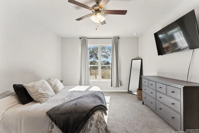 a bedroom with a bed a window and a flat screen tv