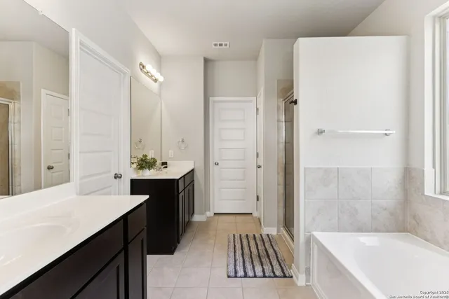 a bathroom with a tub sink shower and two mirror
