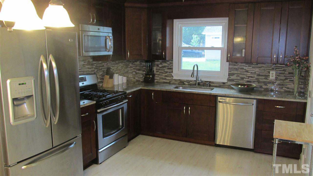 4823 Revere Road Durham, NC 27713 - Photo 4 of 15 a kitchen with stainless steel appliances granite countertop a sink stove and refrigerator