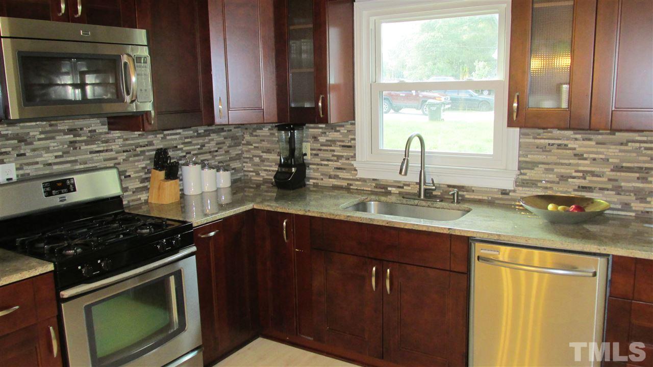 4823 Revere Road Durham, NC 27713 - Photo 5 of 15 a kitchen with granite countertop a stove sink and cabinets