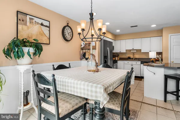 a kitchen with stainless steel appliances kitchen island granite countertop a dining table chairs and a refrigerator