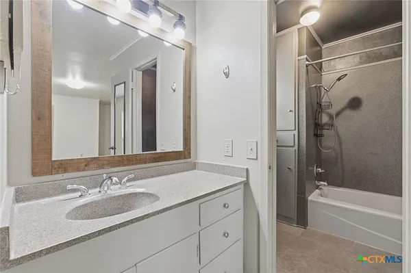 a bathroom with a sink tub vanity and a mirror