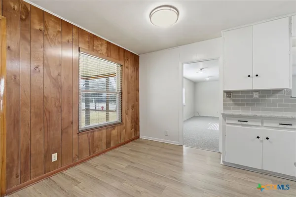 an empty room with wooden floor and cabinet
