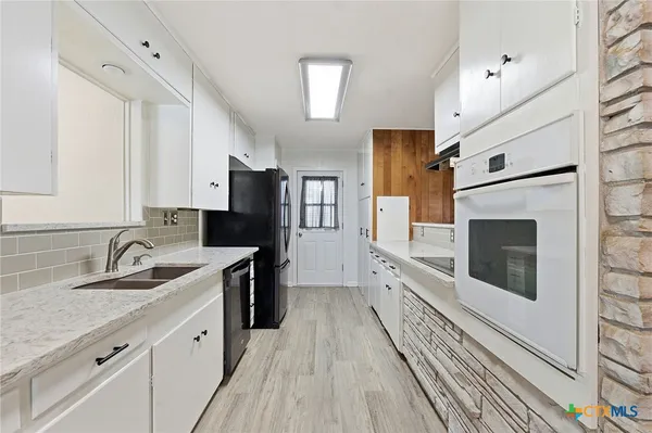 a kitchen with granite countertop a sink a counter space stainless steel appliances and cabinets