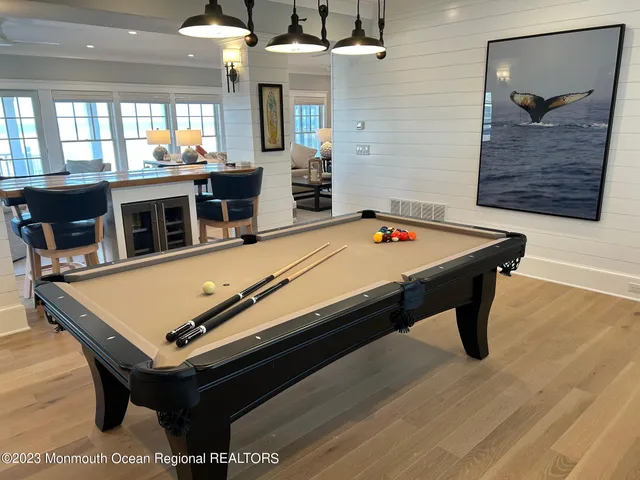 a room with pool table a flat screen tv and windows