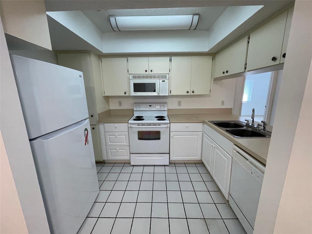 9000 Griggs Road, Unit C Englewood, FL 34224 - Photo 6 of 14 a kitchen with a refrigerator sink stove and cabinets