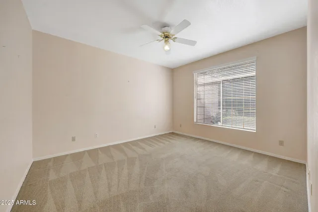 an empty room with windows and fan