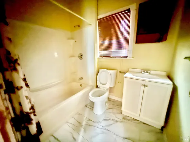 a view of a hallway with wooden floor and a bathroom