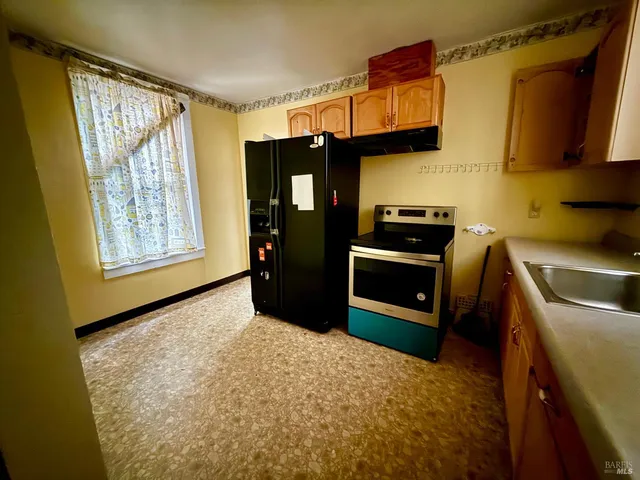 a kitchen with granite countertop a refrigerator and a stove top oven
