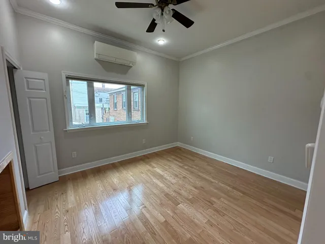 an empty room with wooden floor chandelier fan and windows