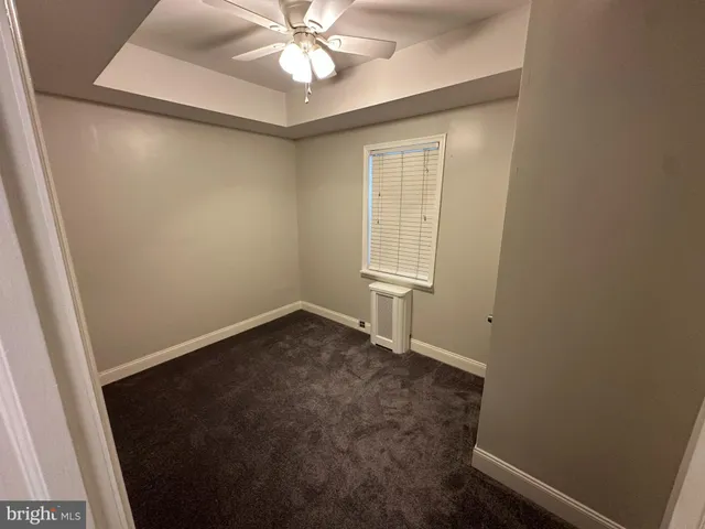 an empty room with a mirror and a ceiling fan
