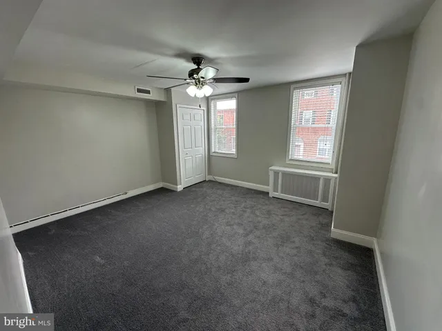 an empty room with windows and fan