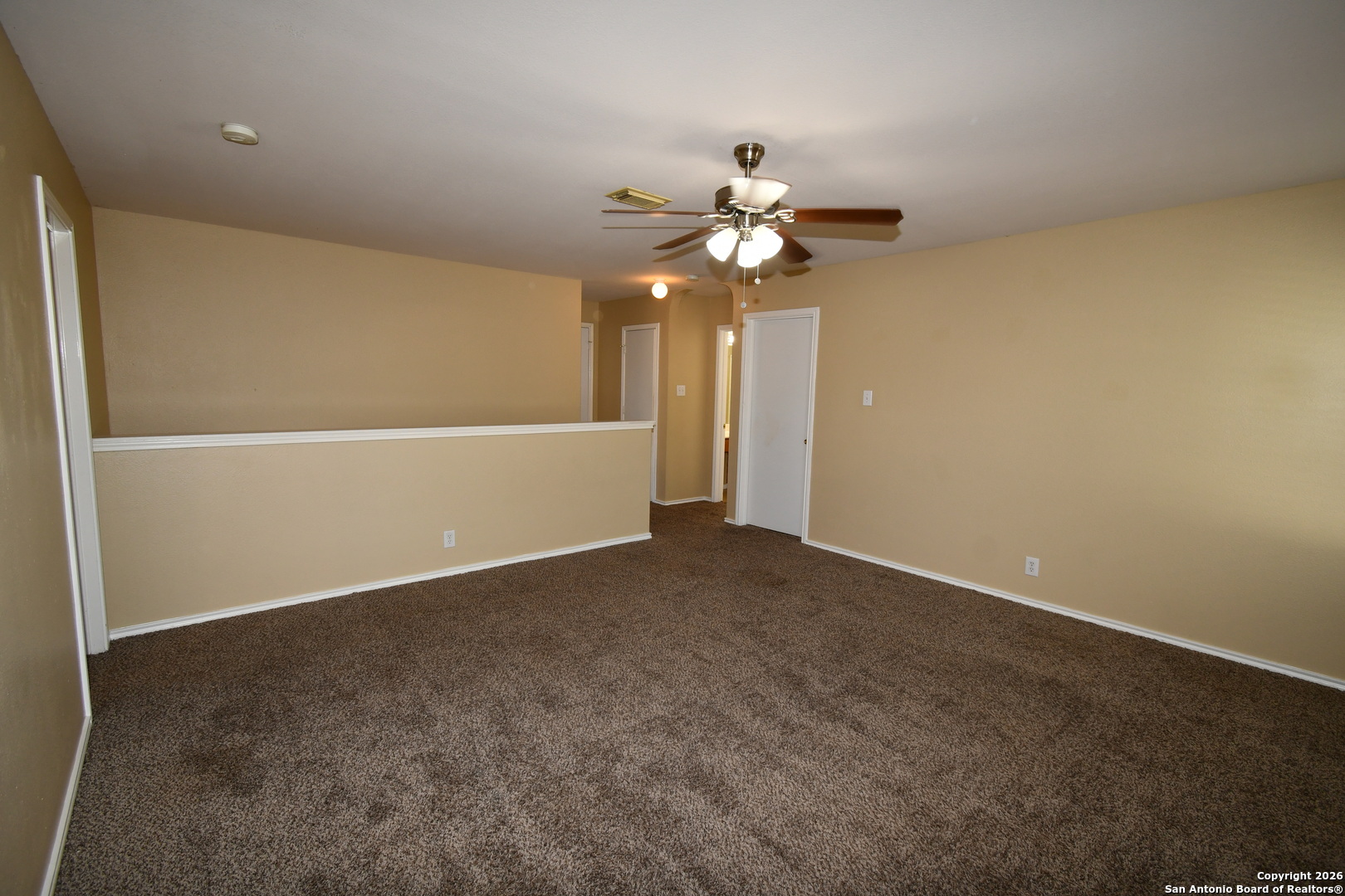 8834 Ridgefront San Antonio, TX 78250 - Photo 15 of 20 an empty room with a chandelier fan and windows
