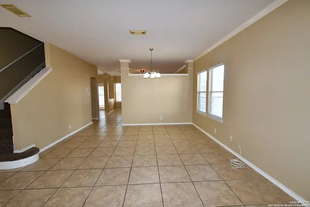 a view of an empty room with window and chandelier fan