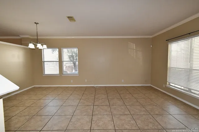 an empty room with chandelier fan and windows