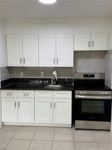 a kitchen with white cabinets and appliances
