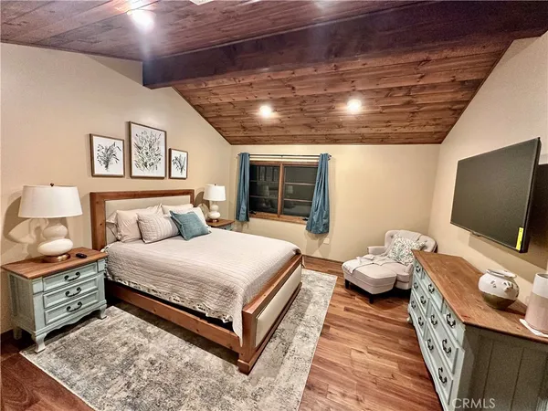 a spacious bedroom with a bed and a flat screen tv