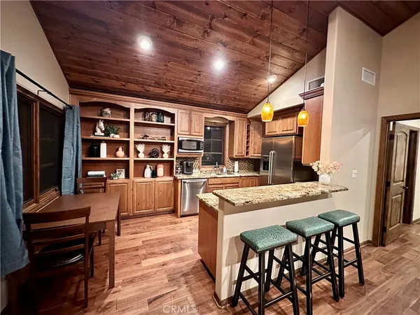 a kitchen with stainless steel appliances kitchen island granite countertop a table chairs and a refrigerator