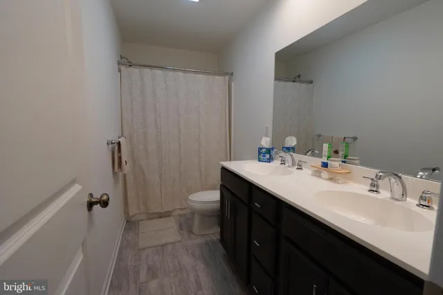 a bathroom with a sink a toilet a mirror and shower