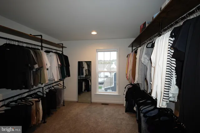 a view of walk in closet with clothes and shoes