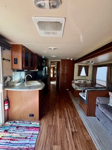 a living room with stainless steel appliances granite countertop a stove and a wooden floors