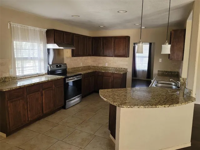 a kitchen with kitchen island granite countertop a sink stove and refrigerator